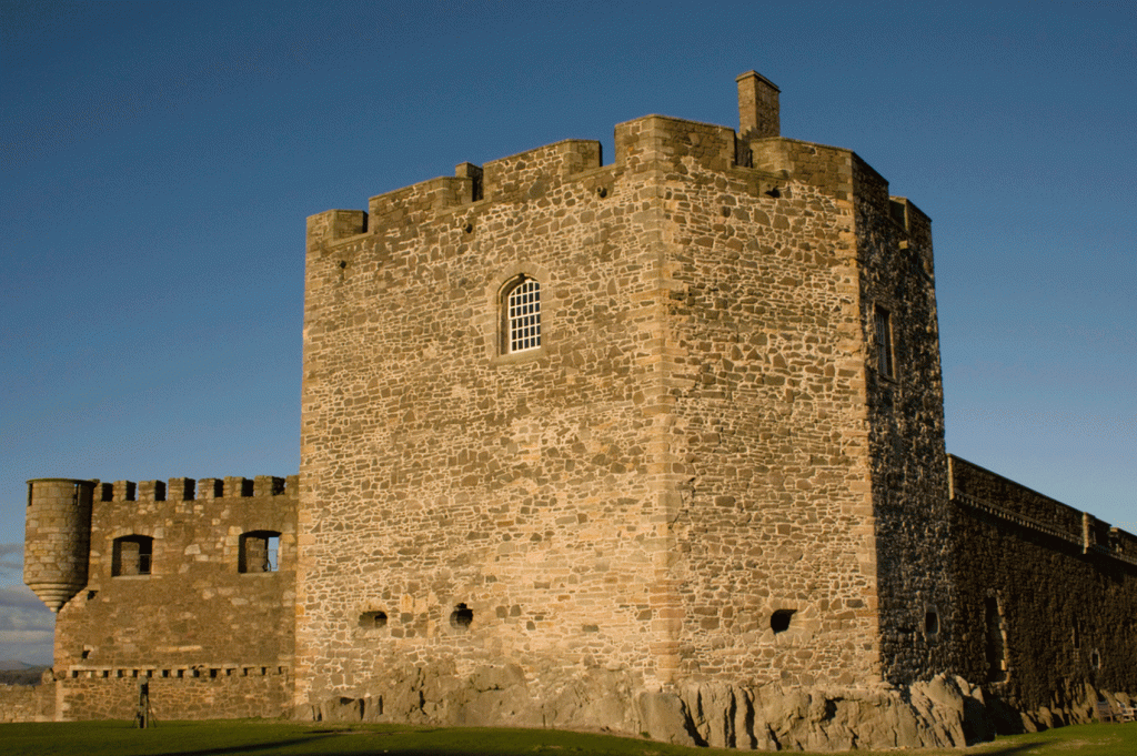 A stone castle with a grassy field in the background.