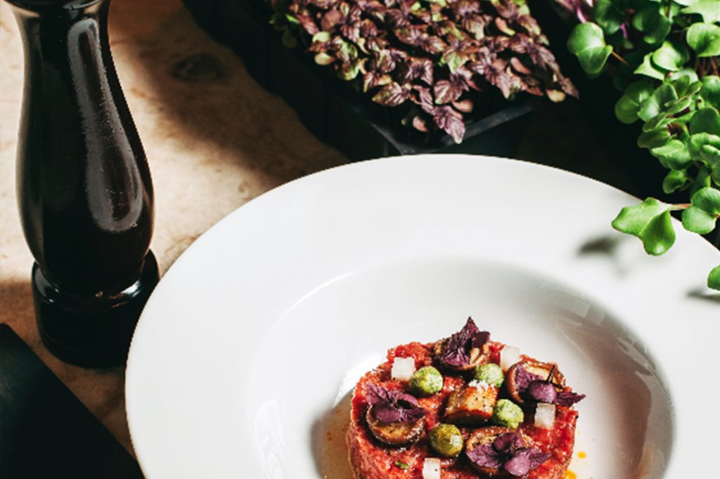 A plate of food on a table next to a bottle of wine.