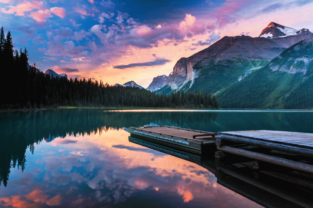 A lake with a dock and mountains in the background.