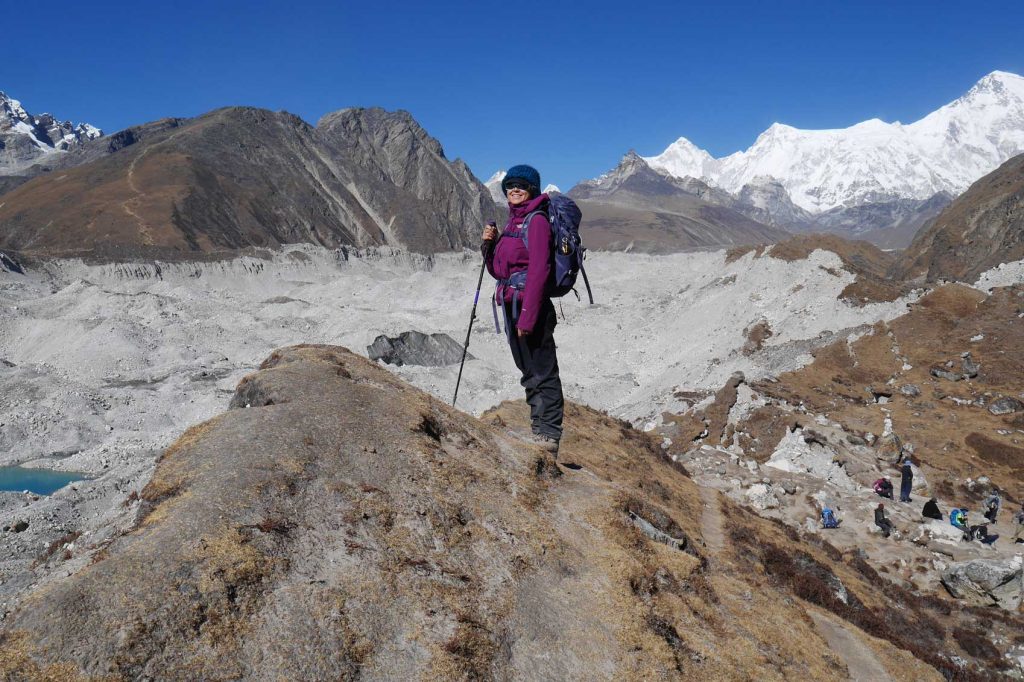 A woman triumphantly standing on top of a mountain, celebrating International Women's Day.