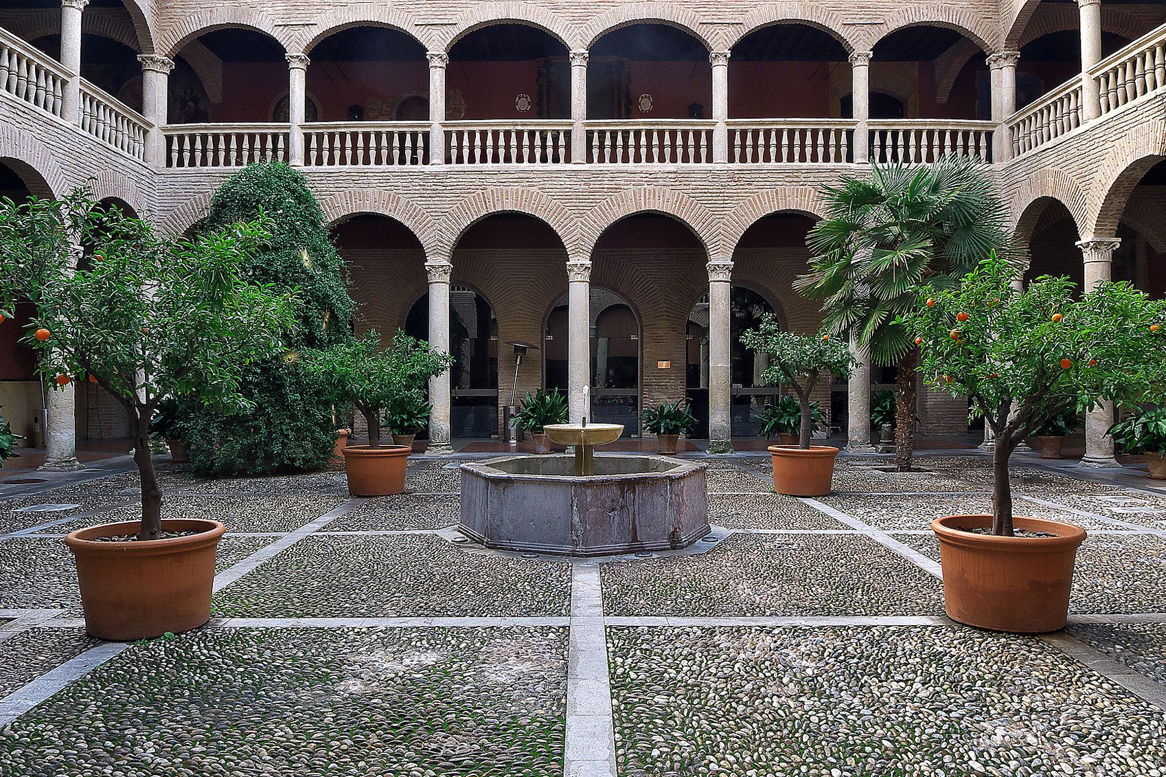 A courtyard in Seville with a fountain and potted plants.