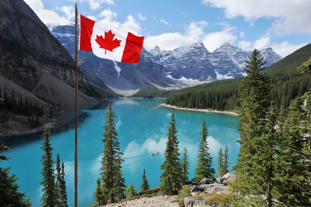 A canadian flag flies over a lake.