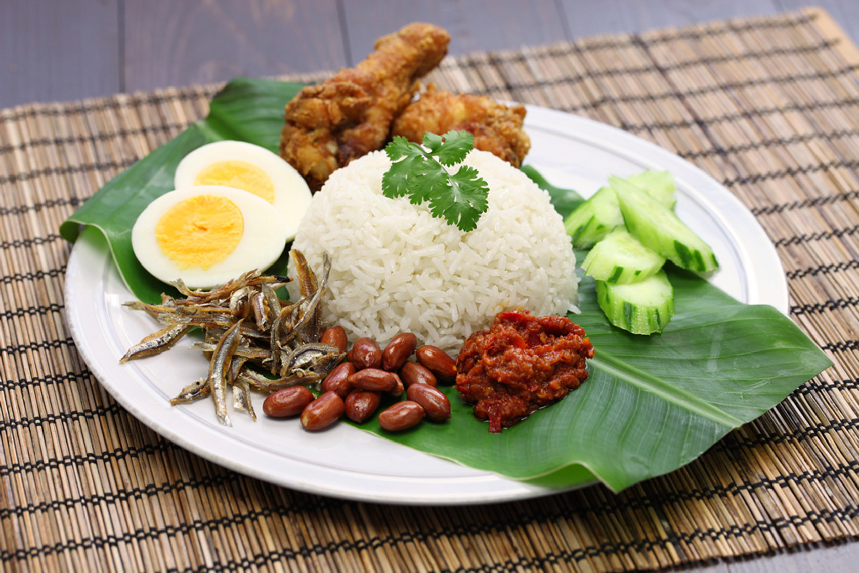 A plate with chicken, rice and vegetables on a banana leaf, representing Southeast Asian Dishes.