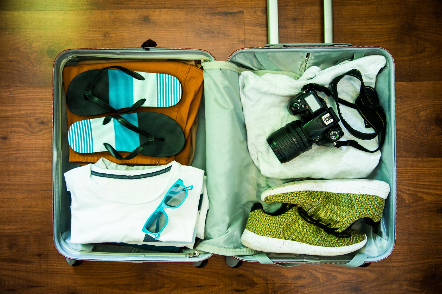 A suitcase packed with travel essentials, including a camera and a pair of flip flops.