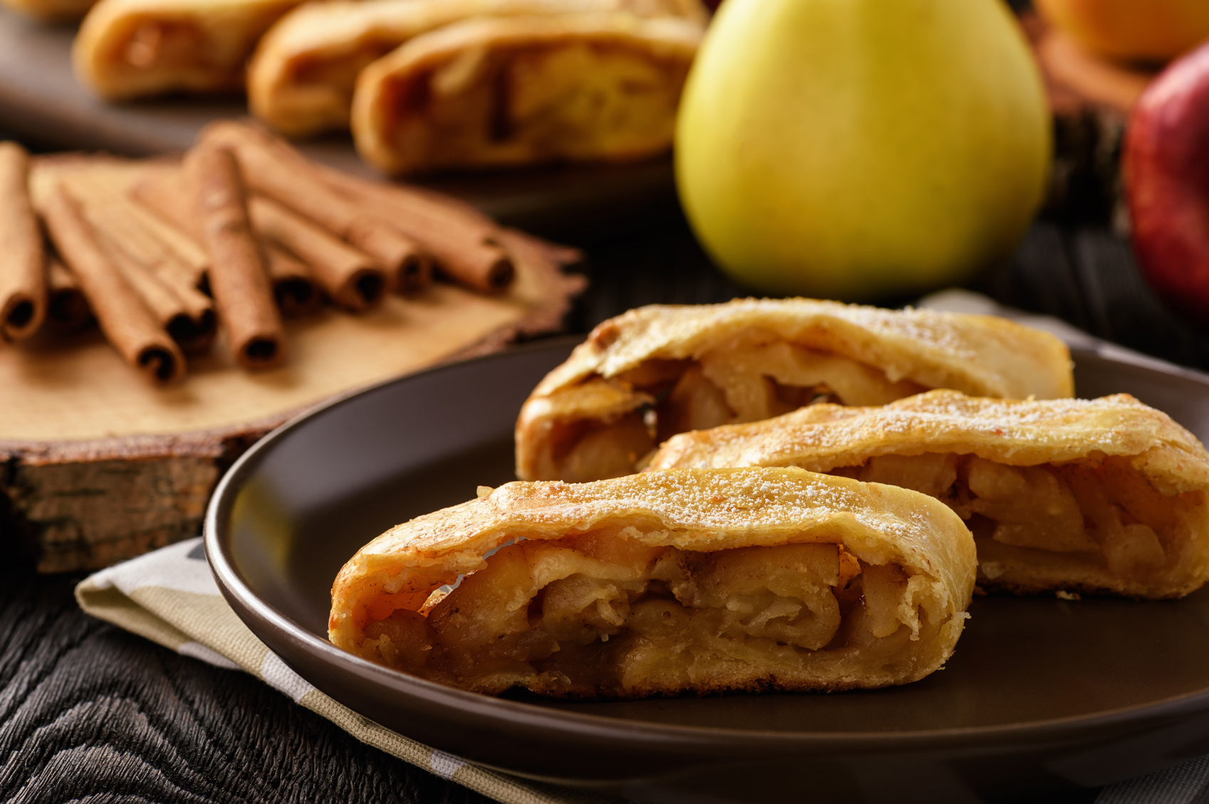 Apple Strudel on a plate with apples and cinnamon in background