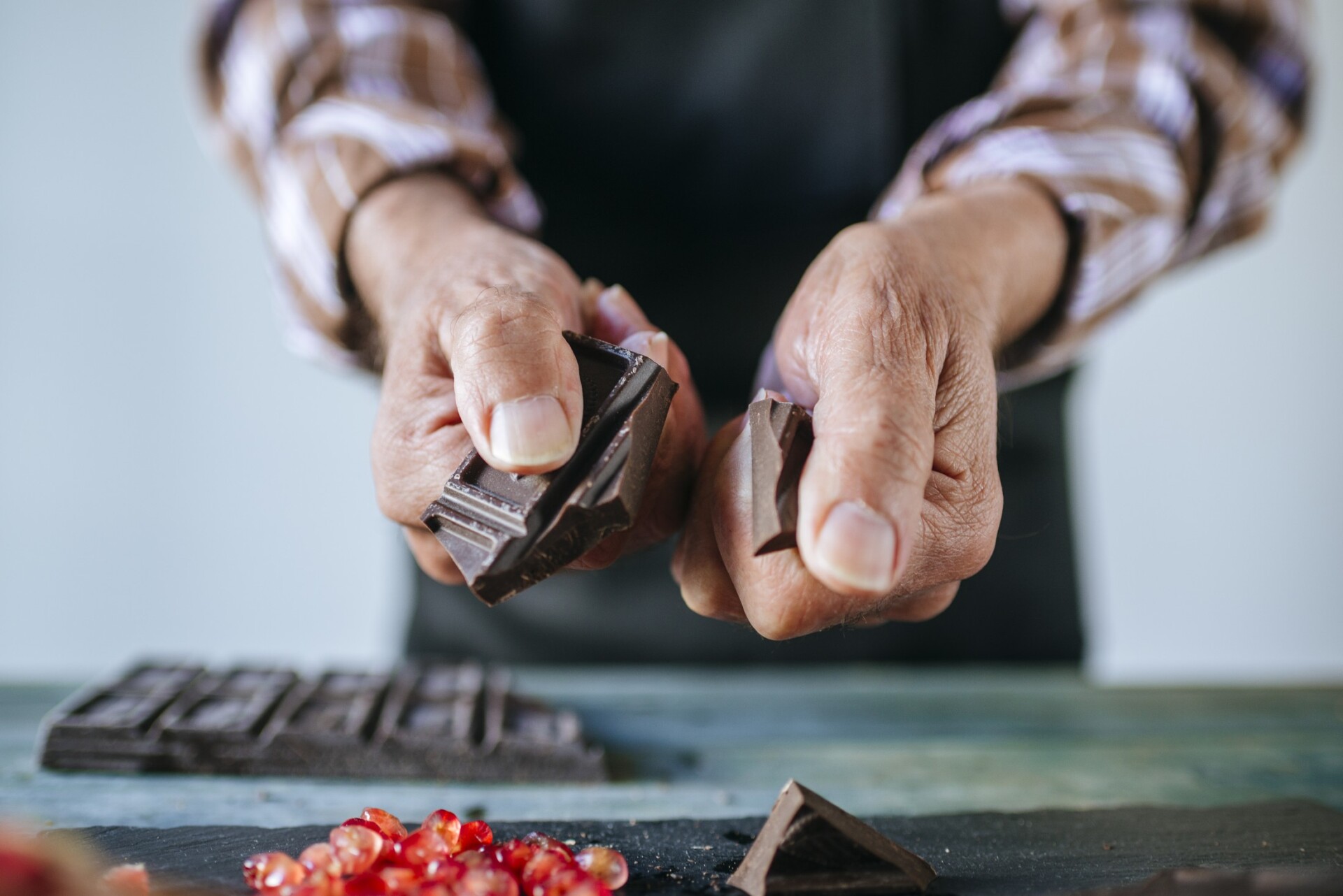 An old man's hands preparing chocolate with pomegranate for a chocolate tasting event.