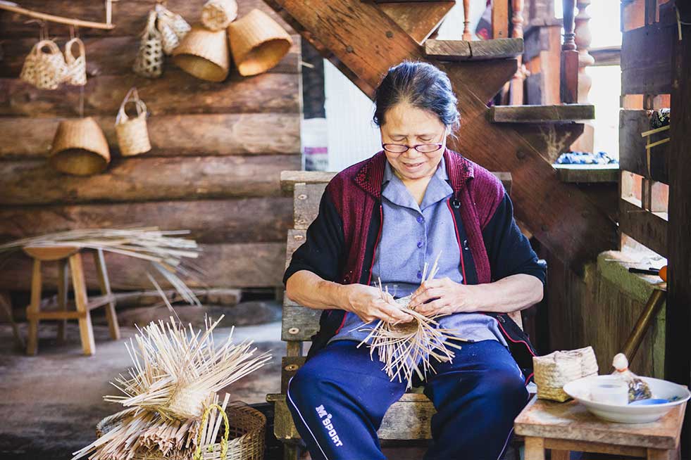 A woman is making baskets in a wooden house in a cool place to visit.