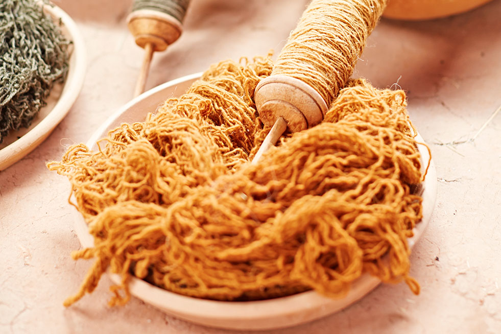 Peruvian women spinning yarn on a wooden wheel.