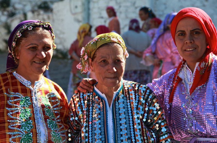 Three local women from Demircidere, dressed in colorful clothing, pose for a picture.