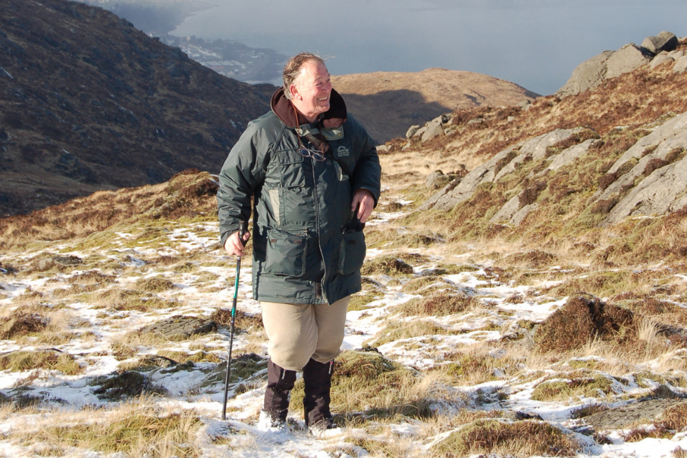 A man is standing on a hill in Ireland, experiencing a unique view.