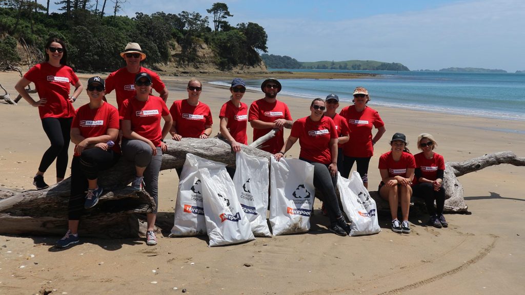 A group of people posing with bags on a beach.