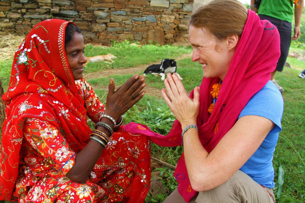 A woman in a red sari is petting a bird.