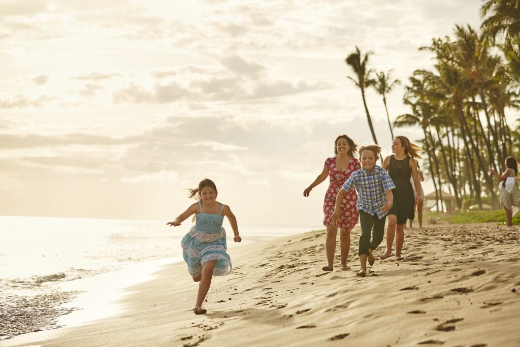 Family running on the beach at sunset.