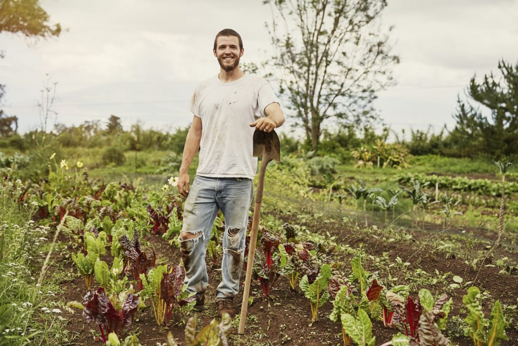 A man standing in a field with a shovel.