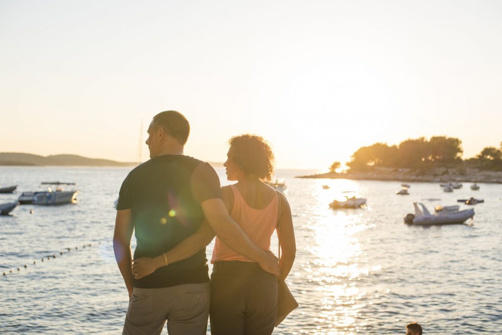 A couple looking out over the water at sunset.