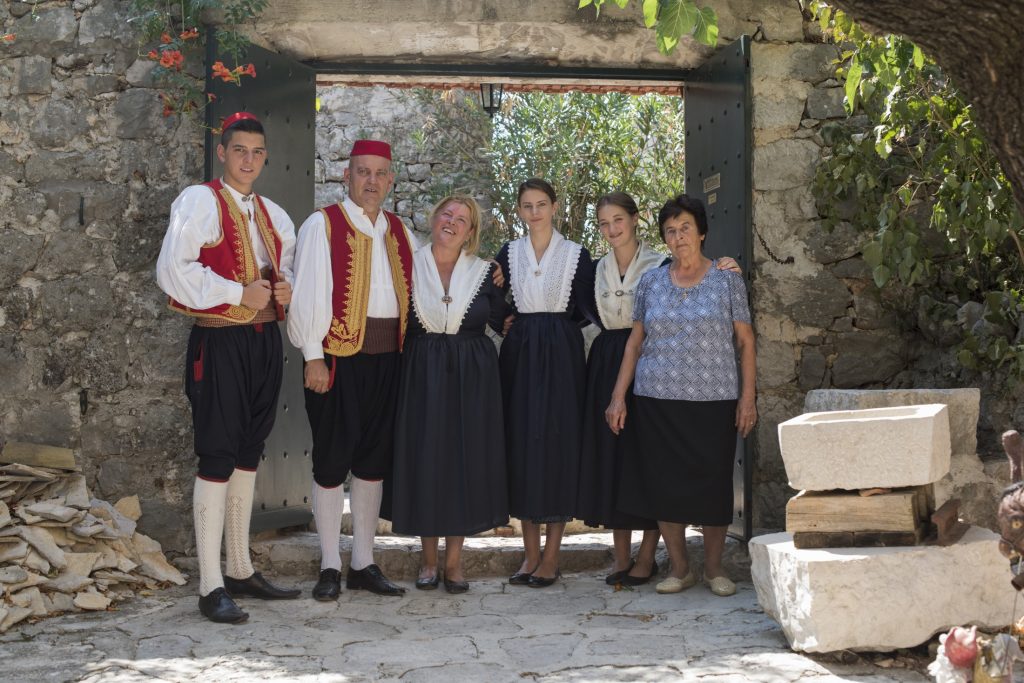 A group of people posing in front of a stone wall at Osojnik.
