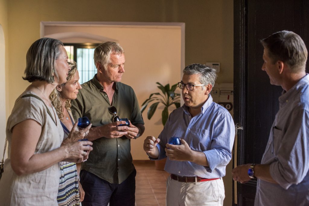 A group of people standing in a room talking to each other.