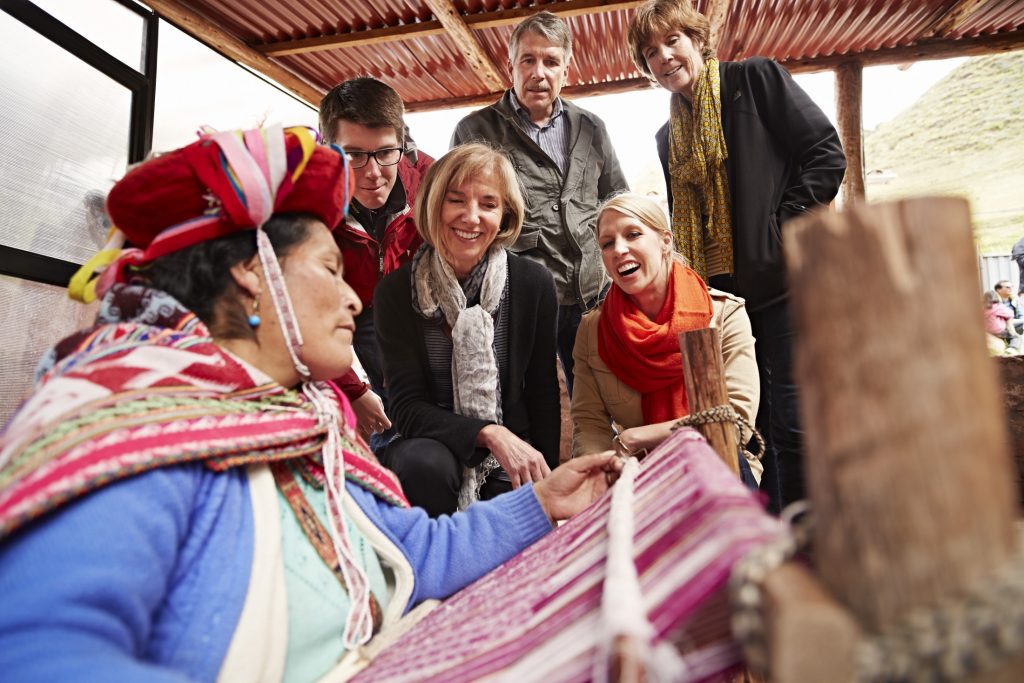 A group of people standing around a weaving loom.