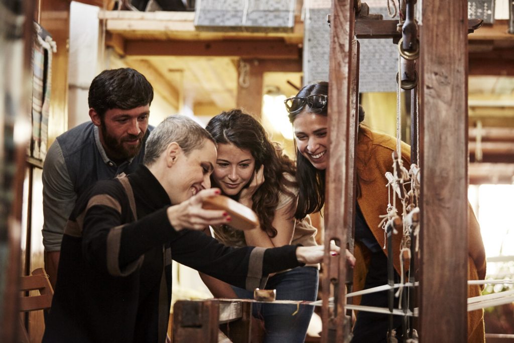 A group of people looking at a weaving machine.