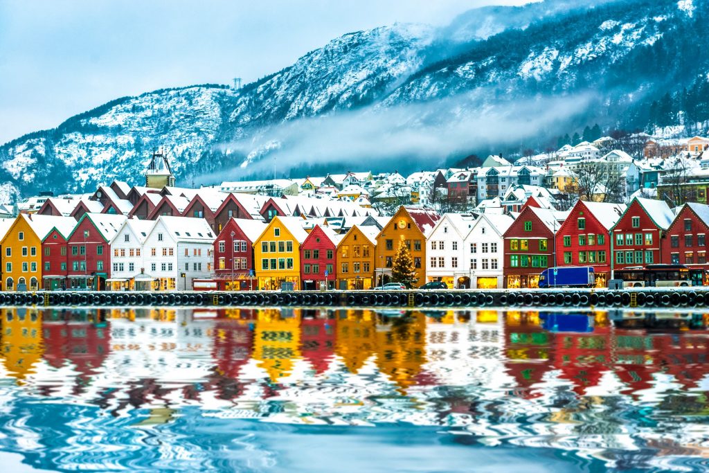 Colorful houses are reflected in a body of water.
