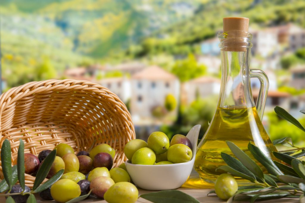 Olives and olive oil on a wooden table.