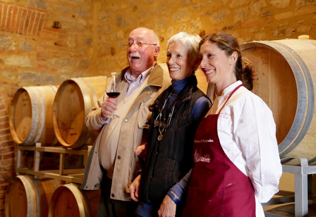 A group of people standing in front of wine barrels.