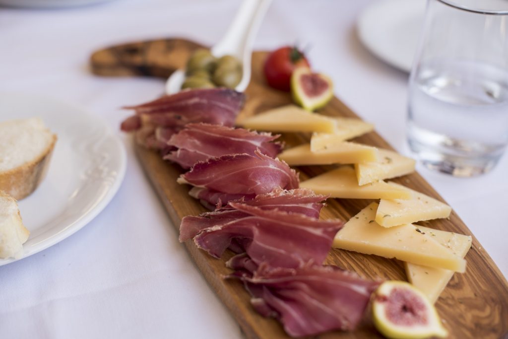 A wooden cutting board with a variety of meats and cheeses on it.