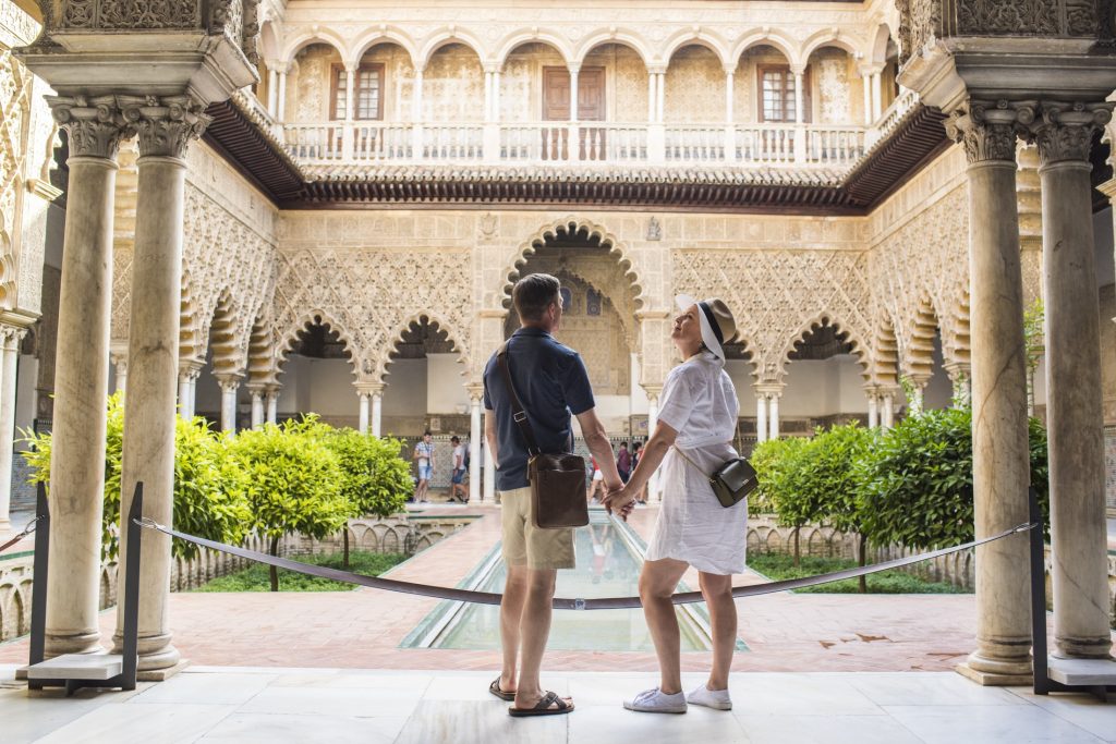 A couple holding hands in an ornate courtyard.