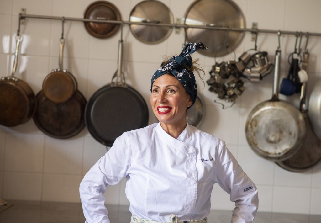 A woman in a chef's uniform standing in a kitchen.