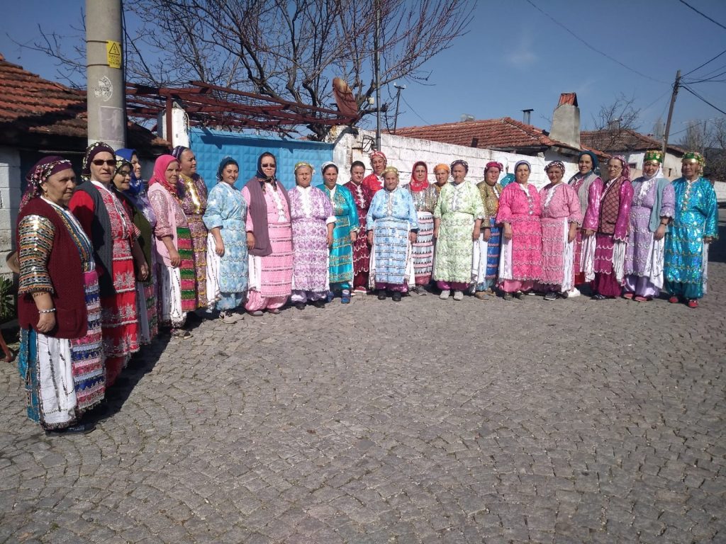 A group of women in colorful clothing standing in front of a cobblestone street.