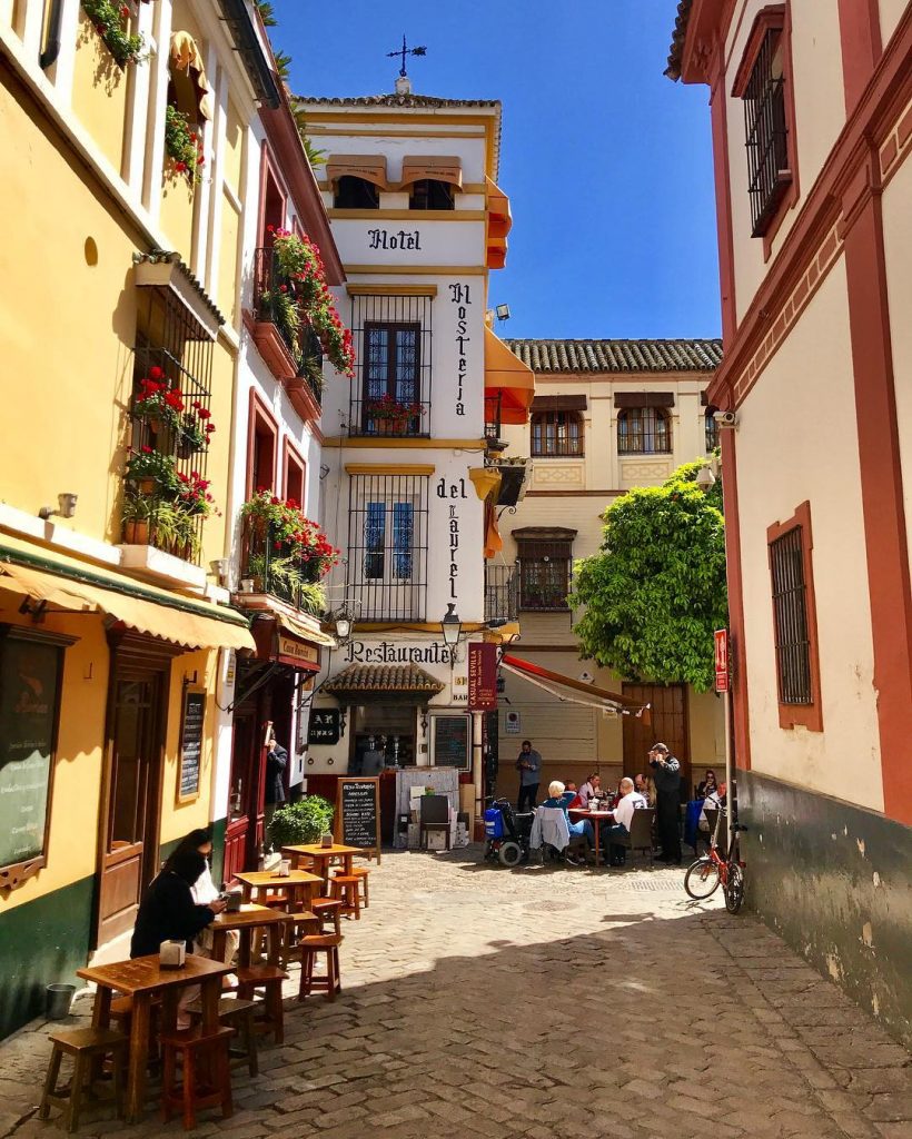A narrow cobblestone street with tables and chairs.
