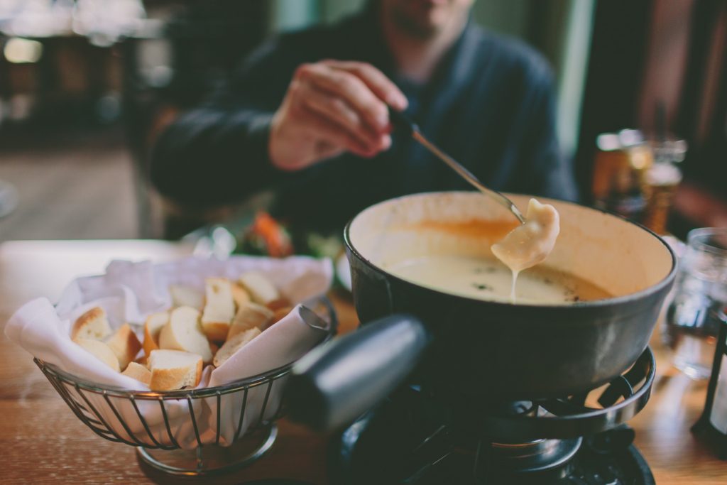 A man is dipping bread into a fondue pot.