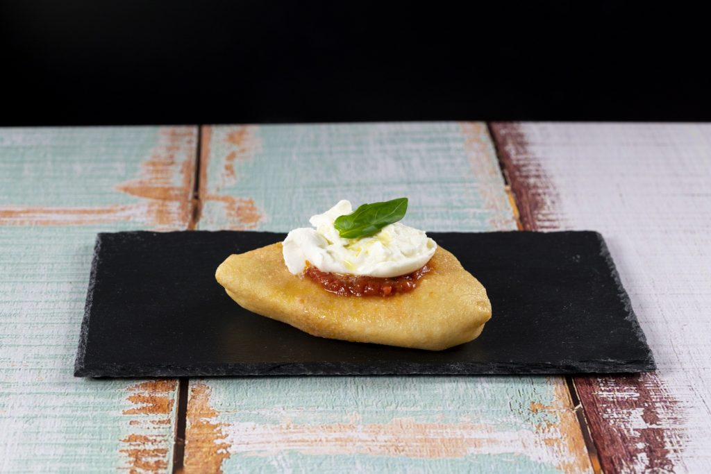 A plate with a pizza with whipped cream and basil on it.