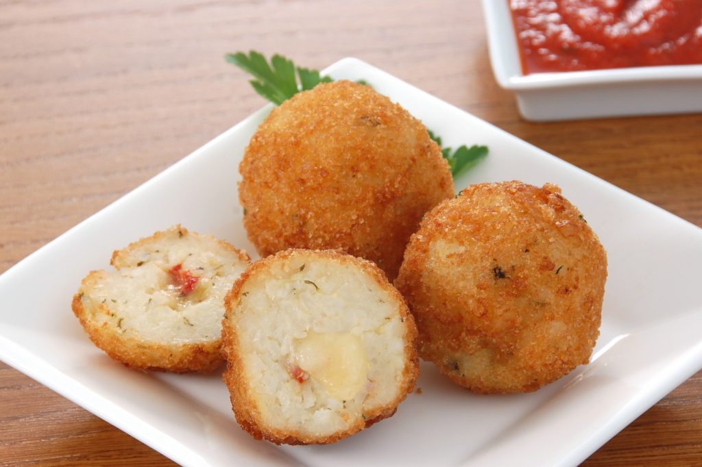 Fried cheese balls on a plate with sauce.