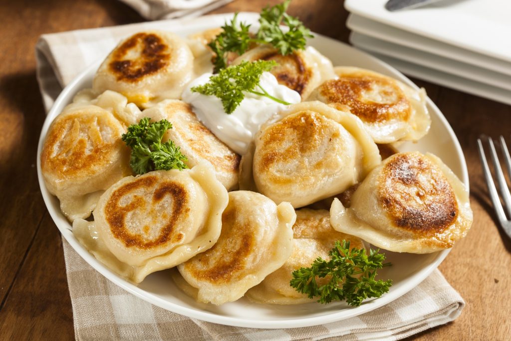 A plate of dumplings with sour cream and parsley.