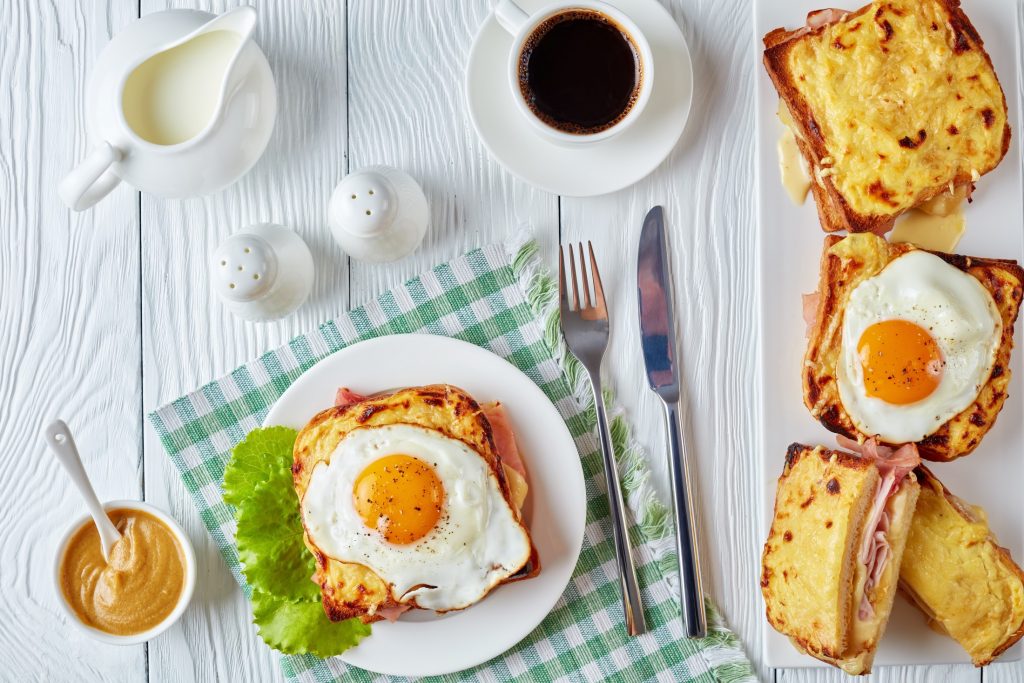 A plate of french toast with an egg on it and a cup of coffee.