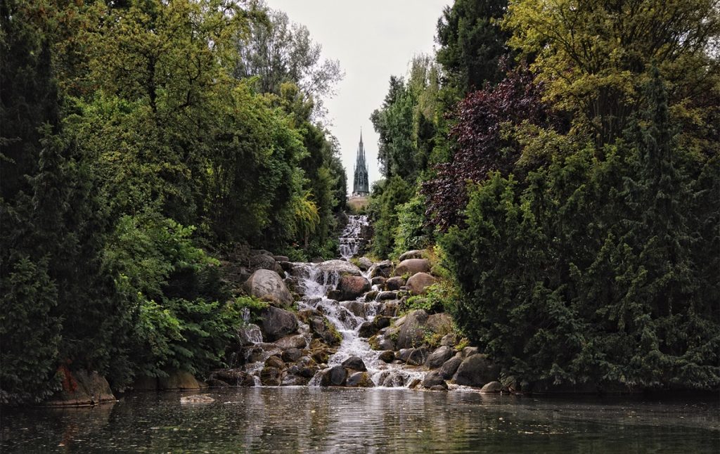 A hidden gem of Germany, this waterfall in a park is surrounded by trees.