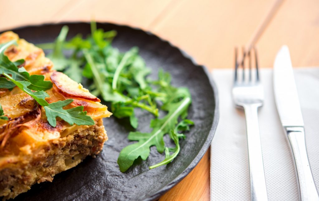 A meat and vegetable casserole with Greek flavors on a plate.