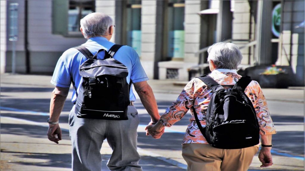 An older couple strolling down the street hand in hand, exemplifying life lessons.