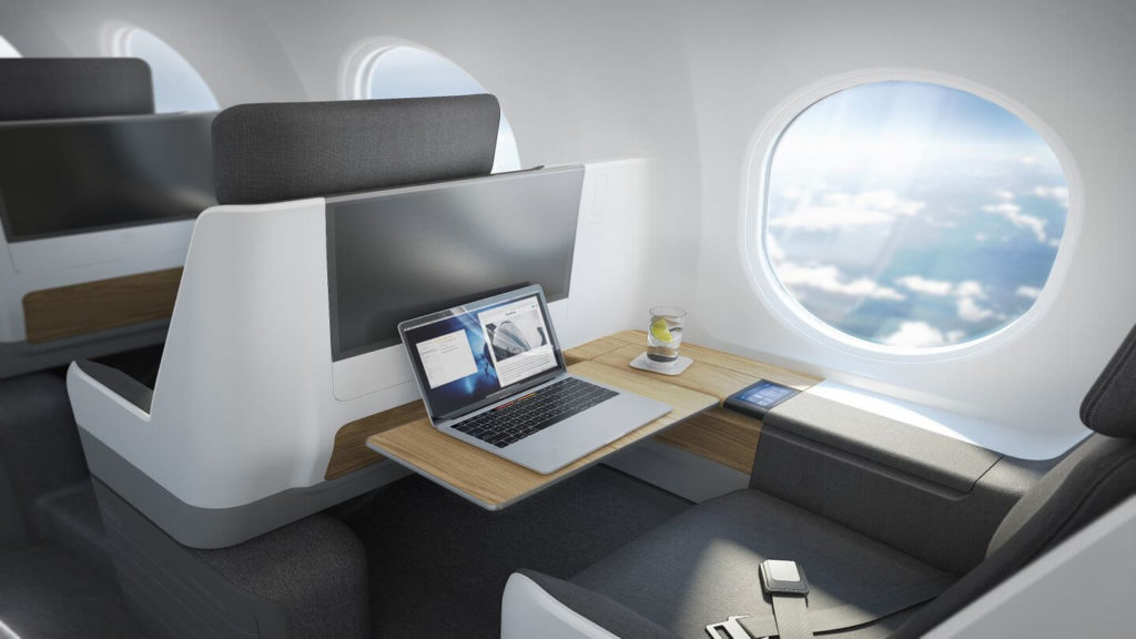 The interior of a supersonic plane with a laptop on a desk.