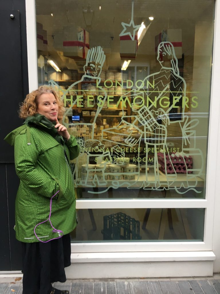 A woman in a green jacket stands in front of a store window.