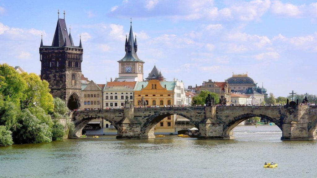 Stone bridge crossing the Danube River in Prague, with church tower in the background