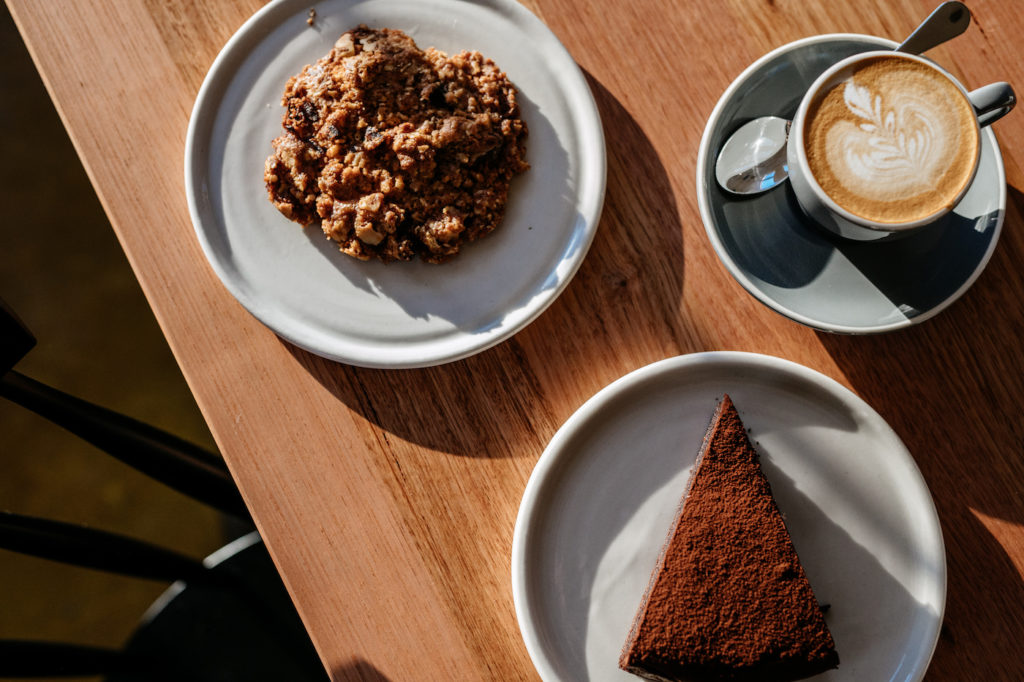 A piece of cake and a cup of coffee on a wooden table in an agrarian kitchen.