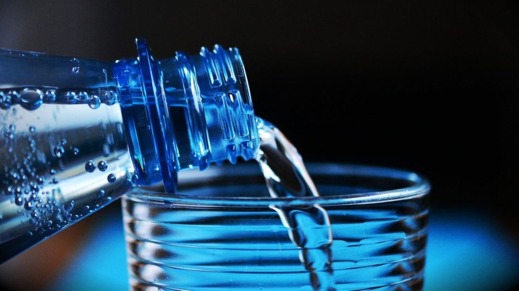 bottle of water pouring into glass