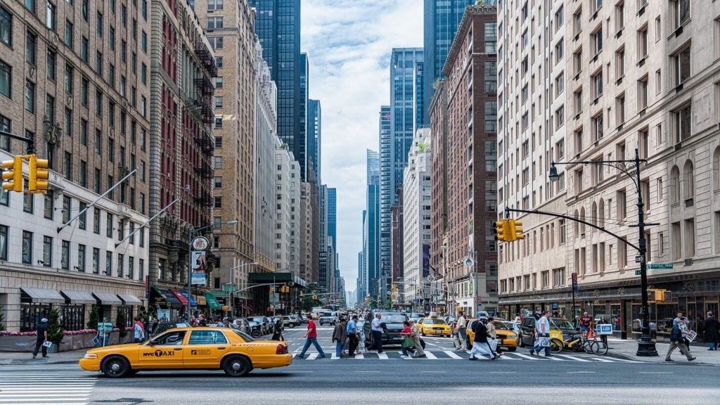 The city  street with tall buildings and yellow taxis is a common sight when traveling in the USA.