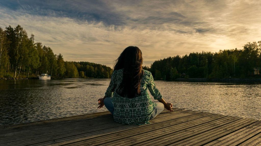 woman meditating by a lake 