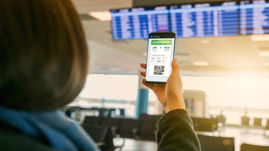 adult holding smartphone with digital boarding pass at an airport