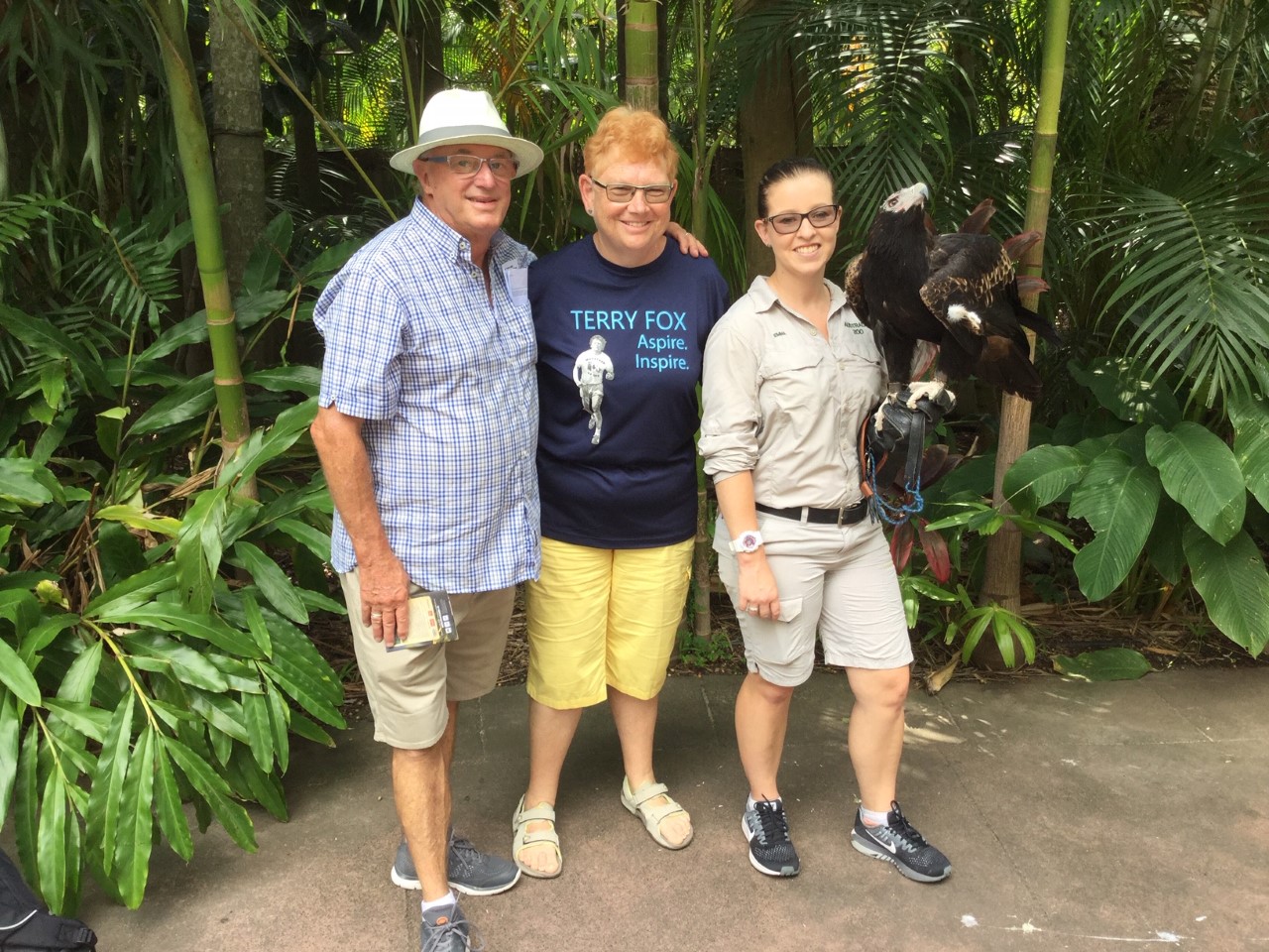 Three people posing for a picture with an eagle while travelling in Ireland.