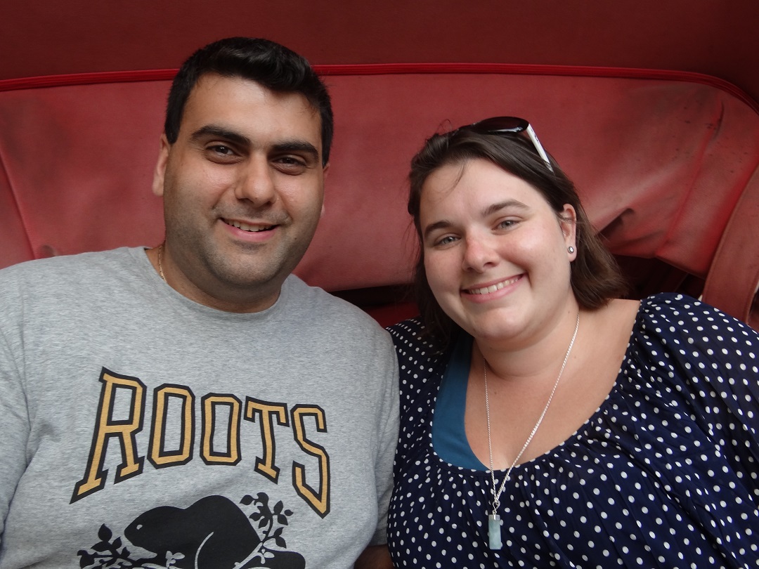 A man and woman smiling while sitting in a red car, touring with Trafalgar.