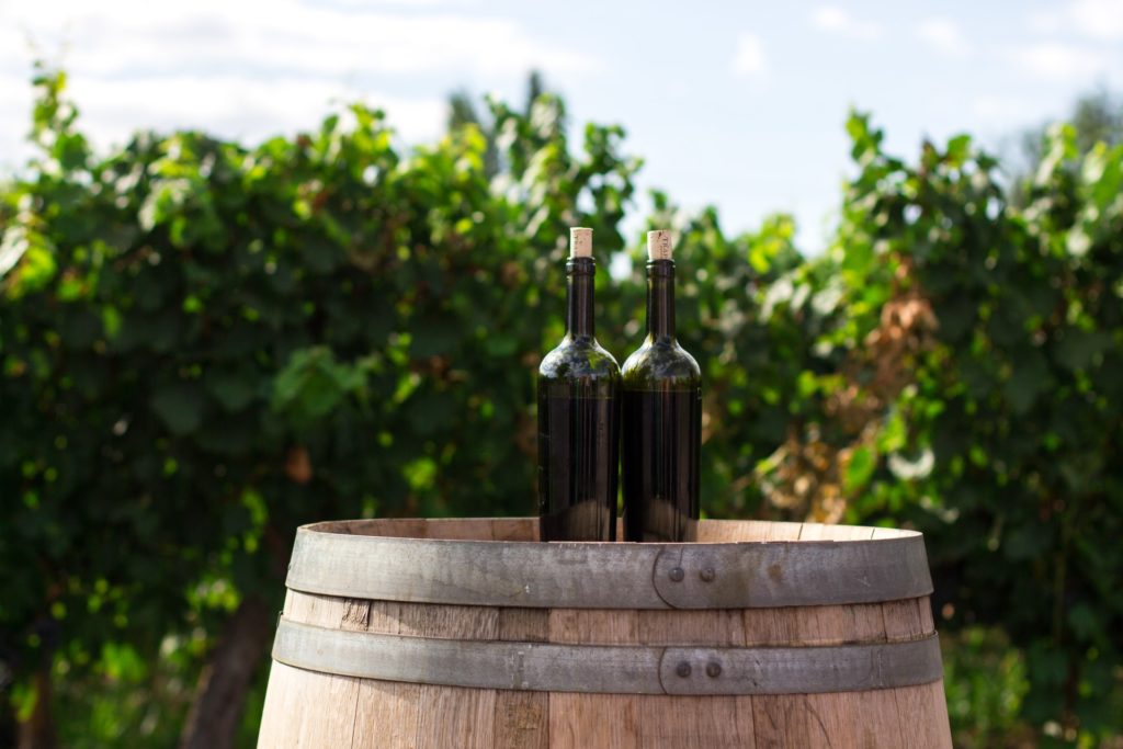Two bottles of the best Chilean wine sit on top of a wooden barrel.
